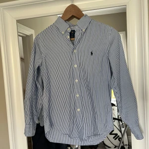 Polo Ralph Lauren skjorta - Tja, säljer nu denna riktigt feta Polo Ralph Lauren skjortan, pga att jag vuxit ur den. Skjortan har inga defekter alls✅ Den är i storlek 12 vilket motsvarar ca 150-160cm. Det är en toppen skjorta på tex fester som får dig att sticka ut bland de andra!💯✅ Det är bara att skriva  om ni har andra frågor och funderingar!😃💯Mvh//Alve