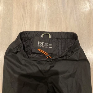 Skallbyxa, junior (Size 152) - Allsidig och fin skallbyxa i vind- och vattentätt material. Reglerbar resårlinning som ger bra passform. Fodrad med snabbtorkad mesh för hög komfort. Reflexdetaljer. 