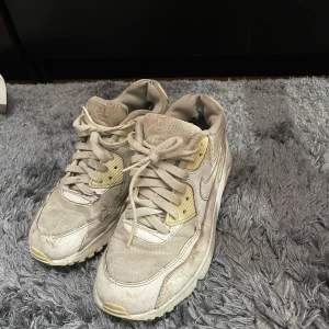 Vita Nike sneakers i storlek 39 - Säljer ett par vita Nike sneakers i storlek 39. De är välanvända men fortfarande bekväma och perfekta för vardagsbruk. Skorna har snörning och en klassisk Nike-design. Perfekta för dig som gillar en sportig stil!