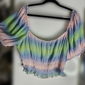 Misslissibell x NA-KD pastell offshoulder topp - Flerfärgad offshoulder topp i mesh från Misslissibells kollektion med NAKD i storlek XL. (Passar även L) Den är i pastellfärger som rosa, blå och grön. Toppen är croppad med volangdetaljer i nederkant. Har en pytteliten defekt på ena ärmen som syns på sista bilden. 