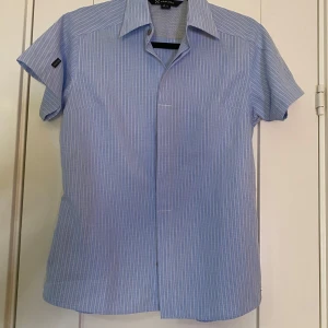 Ny blå och vit randig friluftsblus i strl 38 från Haglöfs - Ny blå och vit randig friluftsblus i strl 38 från Haglöfs.  Ny, aldrig använd.  Mått Över bröstet: ca 50 cm Längd från axeln och ner: ca 60 cm  90% polyester och 10% viskos  Kommer från ett djur och rökfritt hem.