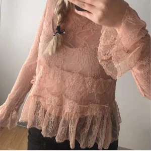 Beige spetsblus - Säljer en superfin rosa spetsblus med volanger. Den har långa ärmar och en romantisk stil som passar perfekt för både vardag och fest. Blusen är i mycket bra skick och ger en elegant touch till vilken outfit som helst.