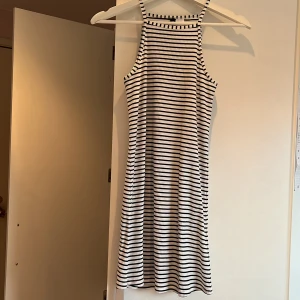 Randig klänning från Divided - Säljer en superfin randig klänning från Divided i storlek 32. Den är ärmlös med smala axelband och har ett stilrent svartvitt randigt mönster. Perfekt för sommardagar eller en avslappnad dag på stan. Materialet är mjukt och bekvämt, vilket gör den lätt att bära hela dagen. Passar bra för barn. Helt oanvänd och kommer från ett djur och rökfritt hem!