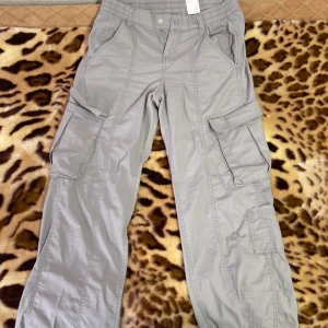 Grå cargobyxor från H&M - Säljer ett par grå cargobyxor från H&M i storlek S. De har flera praktiska fickor och en bekväm passform med elastisk midja. Perfekta för en avslappnad stil eller äventyr utomhus. 🕶️