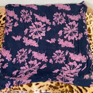 Blommig slöja i blått och rosa - Säljer en superfin blommig slöja i blått med rosa blommor. Perfekt för sommardagar eller en mysig vårutflykt. Slöjan har en avslappnad passform och är gjord i ett lätt och luftigt material. Den är både bekväm och stilren, perfekt för att liva upp garderoben!