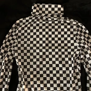 Svartvit rutig polo body från Shein - Säljer en cool svartvit rutig polo body från Shein. Den har långa ärmar och en hög krage som går att vika ner. 🖤🤍Den är gjord i mesh-tyg vilket innebär att den är genomskinlig. Aldrig använd