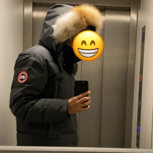 Grå parkajacka med äkta päls  - Säljer en grå parkajacka från Canada Goose med pälsdetalj på huvan. Jackan är perfekt för kalla vinterdagar och har en stilren design med knappar och dragkedja. Den är varm och bekväm, idealisk för både vardag och utomhusaktiviteter.
