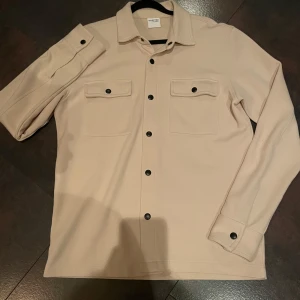  overshirt från selected home - Säljer en snygg beige overshirt från selected home i storlek M. Tvärskönt material o håller värmen hyfsat. Andvänd typ 3 ggr så den är i nyskick. Bara o höra av sig vid frågor! Nypris 800 ish, mitt pris 450 kr! 