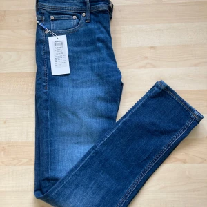 Blå jeans från Jack & Jones - Säljer ett par snygga blå jeans från Jack & Jones i modellen Glenn. De är i slim fit och har en klassisk femficksdesign med knappgylf. Perfekta för både vardag och fest! 🕺