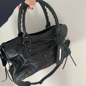 Svart trendig väska - Säljer den här svarta väskan som liknar en annan väska från ett annat märke. Den är cirka 40 cm lång och endast använd ett fåtal gånger så den är i princip i nyskick💗