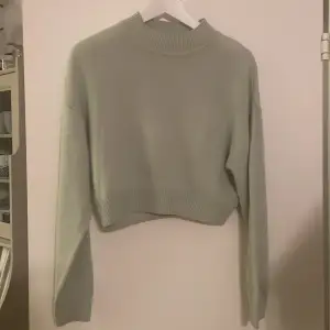 Säljer en superfin grön croppad tröja från H&M Divided i storlek XS. Den är stickad och har långa ärmar med en ribbad hög krage. Perfekt för höst och vår när du vill vara både stilren och bekväm. Tröjan är i mycket bra skick och redo för nya äventyr! 🍃