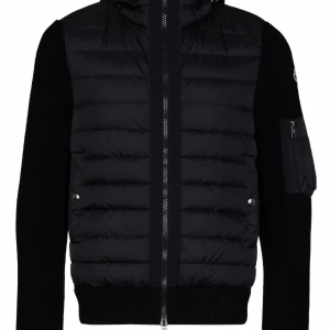 Moncler vadderad jacka med stickad detalj i Stl. S - Säljer en snygg svart vadderad jacka med stickad detalj från Moncler. Jackan har en quiltad design med dragkedja och långa ärmar. Perfekt för höst och vinter, håller dig varm och stilren.  •Fodrad design •Quiltad finish •Huva med dragsko •Ärmar i kontrasttyg •Armficka med blixtlås •Två passpoalfickor på sidan texturerad finish •Dubbelsidig dragkedja fram