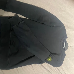 Svart tröja från Stone Island - Säljer en svart tröja från Stone Island i mycket bra skick. Den har långa ärmar och det ikoniska märket på ärmen. Perfekt för höst och vinter, och passar både till vardags och fest. Skön och stilren design!         De ingår en Stone island påse och plasten tröjan låg i Priset kan diskuteras  hör av er vid frågor 