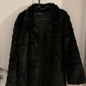 Svart pälsjacka från Primadonna Collection - Säljer en elegant svart pälsjacka från Italien i märket Primadonna Collection. Jackan är perfekt för kyliga dagar och har en lyxig känsla. Den är långärmad och har en mjuk, fluffig textur som håller dig varm och stilren. Passar perfekt för både vardag och festliga tillfällen.