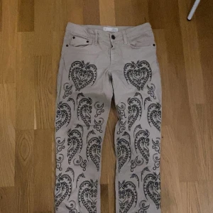 Beige byxor med mönster - Säljer ett par unika beige byxor från Odd Molly med snyggt mönster i svart. Byxorna har en normal passform och är perfekta för att sticka ut lite extra. De har knappar och dragkedja framtill samt fickor både fram och bak. Perfekta för höst, vår och vinter!