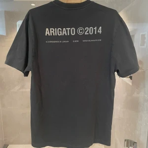 Grå t-shirt från Arigato - Snygg grå t-shirt från Arigato med tryck både fram och bak. Perfekt för en casual look.