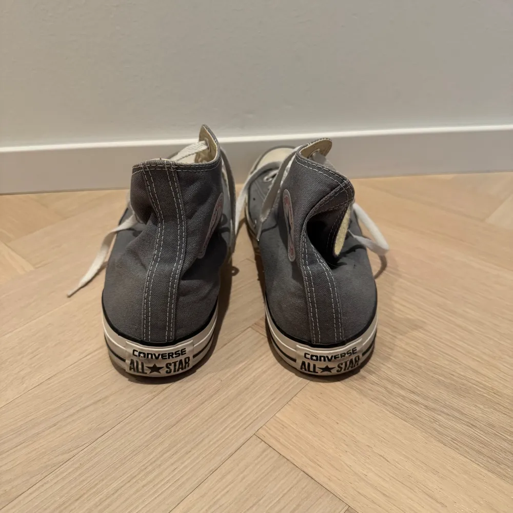 Säljer ett par klassiska grå Converse All Star sneakers i bra skick. De har vit snörning och den ikoniska loggan på sidan. Perfekta för vardagsbruk och passar till nästan allt. Sulan är i gott skick.. Skor.