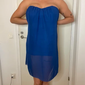 Blå axelbandslös klänning från Jeane Blush - Säljer en snygg blå axelbandslös klänning från Jeane Blush. Perfekt för sommaren med sin lätta och luftiga design. Klänningen har en enkel och stilren look, vilket gör den idealisk för både vardag och fest. Den är i mycket bra skick och redo för nya äventyr!