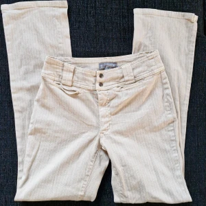Vintagebyxor LiPP - Eleganta byxor med raka ben och låg midja, från märket LiPP! 🌿 Vintage från 80-talet, välbevarade utan defekter! Beige färg med smala, vita ränder. Verklig storkek ~ XS. Midjemått: 34 cm Innerbenslängd: 77 cm Totallängd: 100 cm Benvidd nedtill: 20 cm