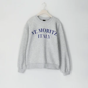 Grå sweatshirt med St. Moritz-tryck - Säljer en snygg grå sweatshirt med blått St. Moritz Italy-tryck. Tröjan är i mycket bra skick och är använd fåtal gånger 