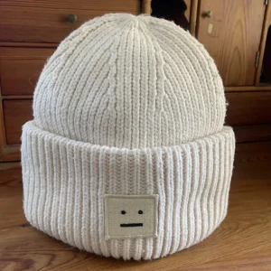 Vit stickad mössa med broderad detalj - Säljer en supermysig vit stickad mössa med en enkel broderad detalj framtill. Perfekt för kalla dagar och ger en stilren look. Passar till det mesta och håller dig varm hela vintern. 🧣❄️