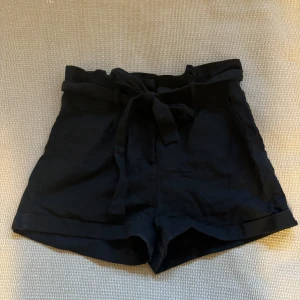Svarta linneshorts med knytband - Säljer ett par snygga svarta linneshorts från lager 157 i storlek XS. De har ett knytband i midjan för en justerbar passform och är perfekta för sommardagar. Shortsen är i mycket bra skick och passar både till vardags och fest. 🖤