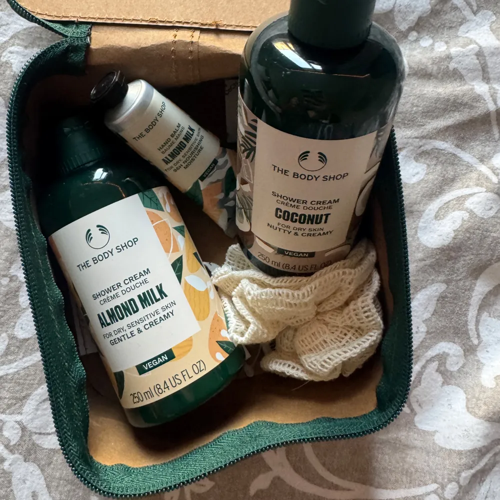 Ett lyxigt presentset från The Body Shop med duschkrämer i dofterna Almond Milk och Coconut, samt en handkräm💛. Perfekt för att ge bort som present! Kommer i en praktisk brun necessär med dragkedja och en mjuk duschsvamp.🤎 Oanvända!✨. Skönhet.