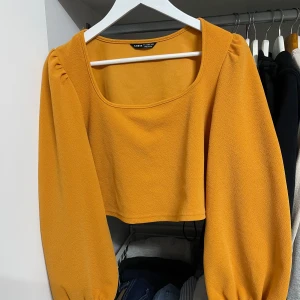 Gul croppad topp från Shein - Säljer en snygg gul croppad topp från Shein. Den har långa puffiga ärmar och en fyrkantig halsringning. Perfekt för både vardag och fest! 🧡