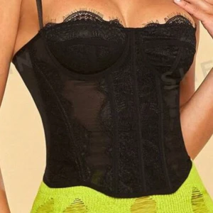Svart spetskorsett - Snygg svart korsett med spetsdetaljer och justerbara axelband. Perfekt för en utekväll eller fest. Den har en elegant design med genomskinliga partier och är väldigt stretchig. Man kan justera storleken där bak på samma sätt som en bh. Jag har aldrig använt den