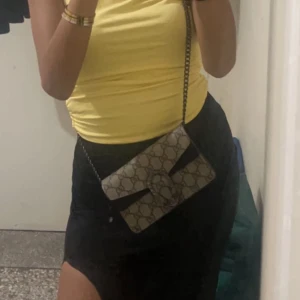 Mini väska  - Säljer en snygg axelväska med kedja och ett coolt mönster. Väskan har en elegant design med en dekorativ spänne framtill. Perfekt för både vardag och fest!