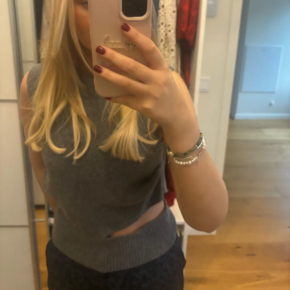 Säljer en snygg grå ärmlös topp med en cool cut-out detalj på sidan. Perfekt för en trendig look och passar bra till både vardag och fest. Toppen är i ett mjukt material och har en tight passform. . Tröjor & Koftor.