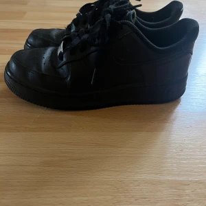 Svarta Nike Air Force sneakers - Säljer ett par svarta Nike Air Force sneakers i bra skick. De har en klassisk design med snörning och är perfekta för vardagsbruk. Skorna har en bekväm passform. Perfekta för både höst och vår!