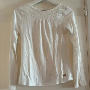 Vit långärmad topp med spetsdetaljer - Säljer en superfin vit långärmad topp med spetsdetaljer vid halsringningen. Perfekt för både vardag och fest! Materialet är mjukt och bekvämt, vilket gör den idealisk för vår och sommar. Passar perfekt till jeans eller kjol. 🕊️ Har lite hål (se sista bilden) men de syns knappt. 