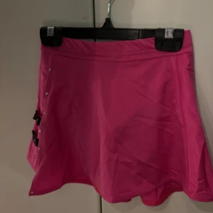 Rosa konståkningskjol från Passionice - Säljer en superfin rosa konståkningskjol från Passionice. Den  svarta banddetaljer och små nitar längs sidan. Den är näst intill aldrig använt så den är i jätte bra skick!