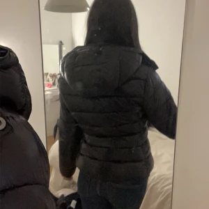 Svart pufferjacka från 157 - Säljer en snygg svart pufferjacka från 157 i storlek XS. Jackan har en praktisk huva och dragkedja framtill. Perfekt för kyliga dagar och ger en stilren look. Använd endast en gång, så den är i mycket bra skick. Passar perfekt till både vardag och fest! 🖤säljer på grund av att den känns lite liten då jag gillar när jackor sitter lite mer baggy💕pris går att diskuteras  enda defekt är initialerna på lappen men går alltid att måla över eller klippa bort 
