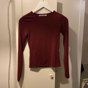 Vinröd långärmad topp - Säljer en stilren vinröd långärmad topp i mycket bra skick. Perfekt för höst och vinter, med en tight passform som sitter snyggt. Materialet känns mjukt och skönt mot huden. Enkelt att matcha med både jeans och kjol för en avslappnad eller uppklädd look. Jag säljer denna topp just för att jag aldrig använder den och känns då onödigt att behålla! Org pris. 100kr. Nytt Pris- 50kr! 💕 Om du vill ha bild när den sitter på så kan jag skicka privat👍🏻