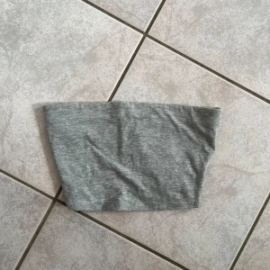 Grå tubtopp från H&M Divided - Säljer en enkel och stilren grå tubtopp från H&M Divided. Perfekt för sommardagar eller som ett basplagg i garderoben. Toppen är i mjukt och bekvämt material. skriv vid frågor💗