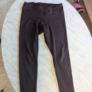 Bruna randiga leggings från H&M - Säljer ett par snygga bruna leggings från H&M Divided. De är randiga och har en hög midja som ger en bekväm passform. Perfekta för både vardag och avslappnade tillfällen. Materialet är mjukt och stretchigt, vilket gör dem superbekväma att ha på sig hela dagen.