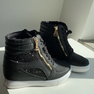Sneakers med klack stl.37 - Svarta glittriga högklackade sneakers med gulddetaljer. Endast använda en gång!! Superfint skick, nästan som nya!💕