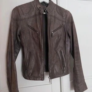 Skinnjacka i äkta läder från Rock n Blue - En bikerjacka i brunt skinn, lite använd så fortfarande i väldigt gott skick! Strl 34 (jag har strl 36/M på tröjor och den här sitter bra på mig för referens) Passa på att klicka hem höstens jacka!