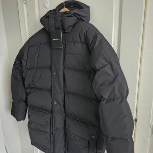 Svart pufferjacka från Peak Performance - Säljer en svart pufferjacka från Peak Performance för 2500kr, org pris 7000kr. Jackan är perfekt för kalla dagar med sin höga fyllkraft på 700 och en blandning av 90/10 dun. Den har en stilren design med broderad logga och praktiska fickor. Jackan är i nyskick och har fortfarande etiketten kvar.