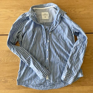Blå och vit randig skjorta från H&M - Säljer en snygg skjorta från H&M:s L.O.G.G.-kollektion. Storlek L/42 men skulle säga M snarare, alltså liten passform. Aldrig använd mycket bra skick🫶