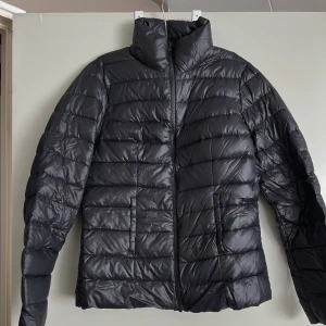 Svart pufferjacka från VILA - Säljer en snygg svart pufferjacka från VILA i storlek M. Jackan har en quiltad design med dragkedja framtill och är perfekt för kyliga dagar. Den är långärmad och har en hög krage för extra värme. Perfekt för både höst och vinter!
