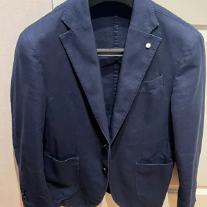 L.B.M 1911 Kavaj Blå - Slim Fit Blazer med enkel knäppning. Lite sportigare och mindre formell. Perfekt när man vill klä ner sig utan att tappa stilen. Tillverkad i Italien. Skick : 10/10. Nypris ca: 5400 kr.