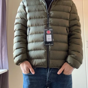 Grön dunjacka från Colmar - Säljer en snygg grön dunjacka från Colmar i storlek S/M. Jackan är perfekt för höst och vinter med sin quiltade design och dragkedja framtill. Den har långa ärmar och en praktisk huva. Perfekt för att hålla dig varm och stilren under kyliga dagar!Priset går att diskutera, mer bilder bara att fråga