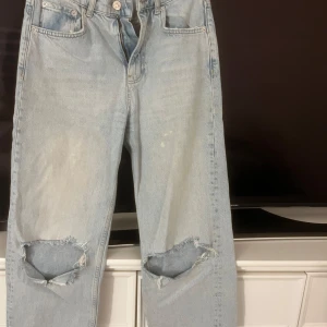 Jeans  - Ett par ljusblåa jeans från Gina med hål på knäna