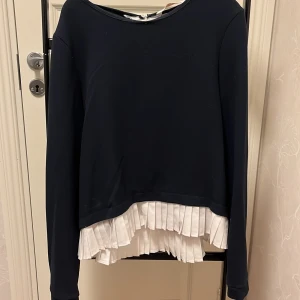 Marinblå tröja med volang - En jättefin marinblå topp med vit volangkant samt vita rosetter