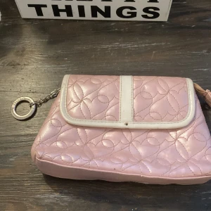Rosa plånbok  - En liten rosa plånbok med hjärtan broderat in. Knappen i mitten på den saknas.
