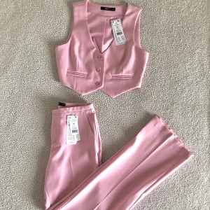 Ginatricot babyrosa kostymset med kavaj, kostymbyxor och väst - Otroligt vacker ljusrosa kostym från Ginatricot med oversize kavaj, lågmidjade kostymbyxor och tillhörande väst. Storlek XS i alla delar men säljer även storlek S i byxorna. Ordinariepris 1600kr för hela setet, säljer även likadant i grönt.