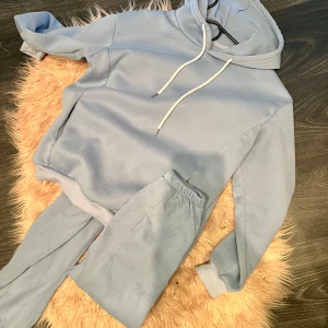 Ljusblå mjukissett - Mysig ljusblå hoodie och byxa i fleece, perfekt för kalla dagar. Den har en justerbar huva med snören och en bekväm passform. Perfekt för att chilla hemma eller ta en promenad i parken. 🧢💙
